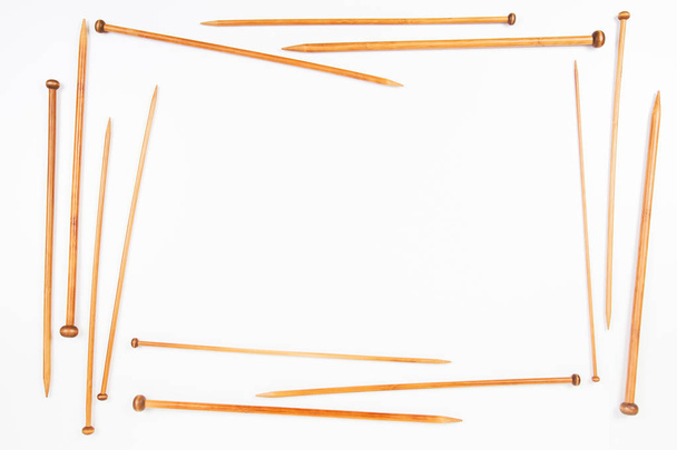 Quadro de agulhas de tricô de madeira em diferentes tamanhos no fundo branco
 - Foto, Imagem