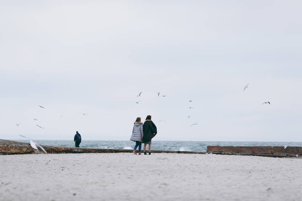 Κοπέλα φορώντας ζεστό παλτό casual μπλε περπάτημα στην παραλία μόνος, θαλασσινό background, κρύο τονισμένο colors.lifestyle εικόνα, όνειρα girl.walking μόνο, Απολαύστε το χρόνο της, sea-gull γύρω, καταιγίδα - Φωτογραφία, εικόνα