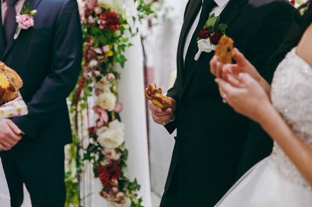 Closeup photo of bride and groom breaking traditional loaf - Zdjęcie, obraz