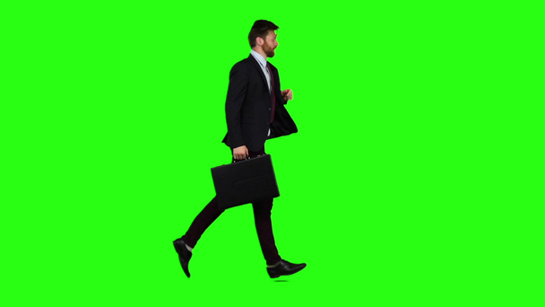 Businessman holds a briefcase in his hand, he rushes over it. Green screen. Slow motion - Footage, Video