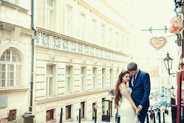 Smiling newlyweds are hugging while spending time in the ancient street in Prague. - Foto, Imagen