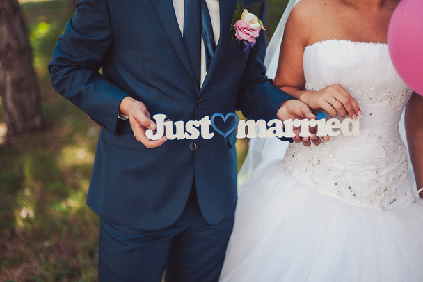 Bruid en bruidegom bedrijf kleine schoolbord met bericht Just Married - Foto, afbeelding