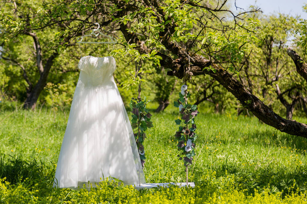 El parque cuelga de un árbol un vestido de novia y un columpio sumergido en flores artificiales
 - Foto, imagen