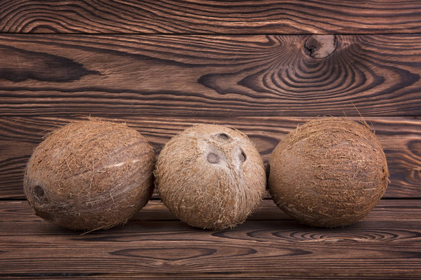 Exotic, tropical and organic coconuts on a dark brown wooden background. Two whole and healthy nuts. Bright brown coconuts. Tropical fruits. - Valokuva, kuva