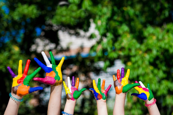 Les mains des enfants peintes dans des couleurs vives isolé sur fond de nature
 - Photo, image