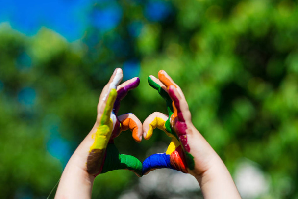 Kinderhände in hellen Farben bemalt machen eine Herzform auf Sommer Natur Hintergrund - Foto, Bild