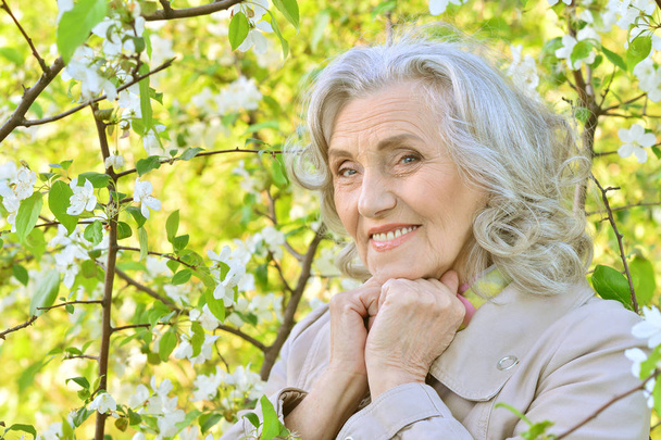 senior woman near blooming tree - Φωτογραφία, εικόνα