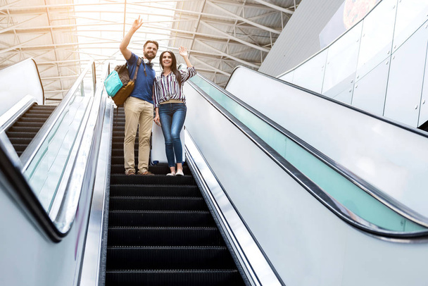 Joyful couple is standing on escalator and expressing gladness - 写真・画像