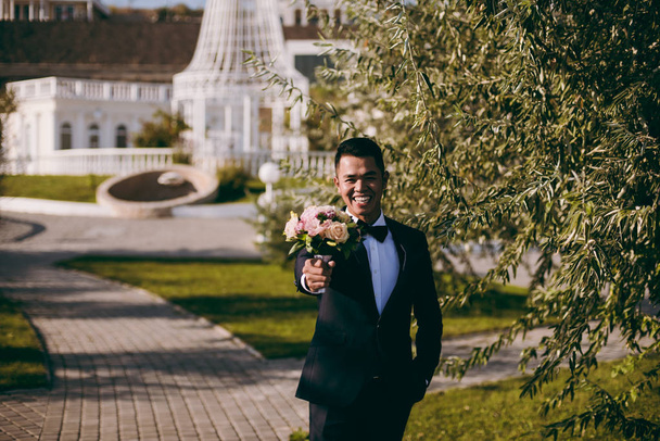 Groom with bouquet on a promenade on the waterfront - Foto, immagini