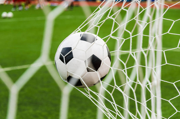 Soccer football in Goal net with green grass field. - Фото, изображение