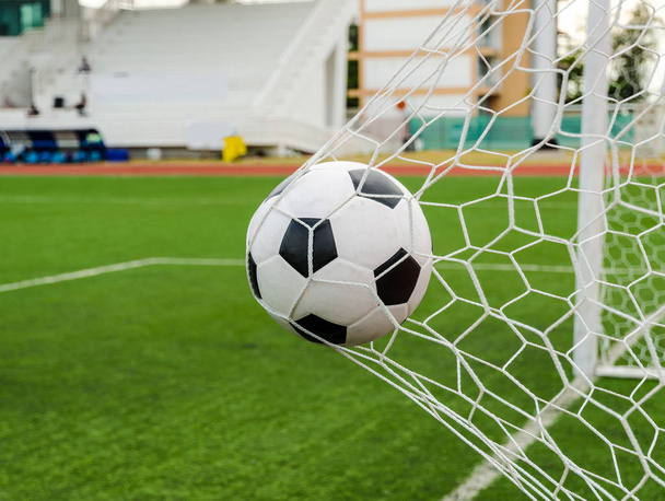 Soccer football in Goal net with green grass field. - Photo, Image