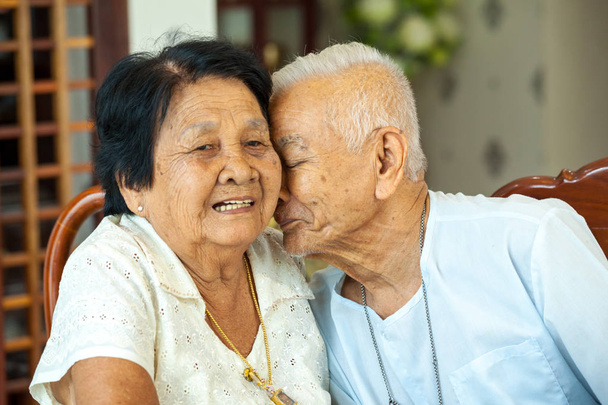 Старший азиатский мужчина целует старшую женщину
 - Фото, изображение