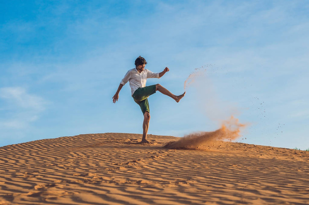 man is kicking sand in a red desert - Zdjęcie, obraz