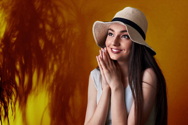 Portrait of surprised a smiling pretty girl in summer hat posing isolated over yellow tropic background.Cocnept summer happines - Fotoğraf, Görsel