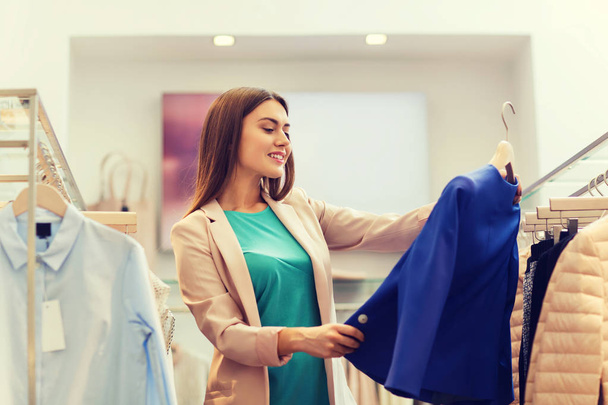 happy young woman choosing clothes in mall - Φωτογραφία, εικόνα