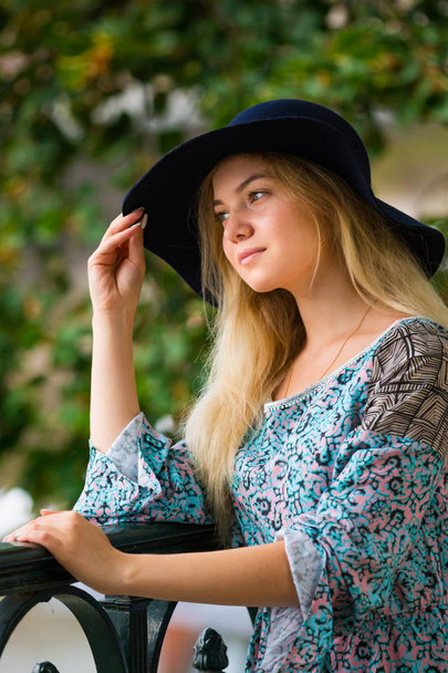 Portrait of fashionable blond girl with hat on embankment in summer day - Foto, afbeelding