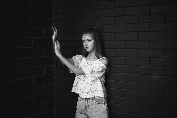 pretty cute young woman posing against the wall of black brick - Photo, Image