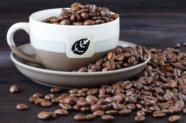 Nahaufnahme einer Tasse Espresso mit frischen Bohnen auf einem Holztisch - Foto, Bild