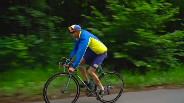 Чоловік середнього віку їде на шосейному велосипеді вздовж лісової дороги, повільний рух
 - Кадри, відео