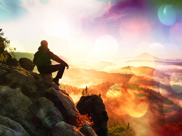 Film effect.Hiker man take a rest on mountain peak. Man lay on summit, bellow autumn valley. Bright morning Sun - Photo, Image