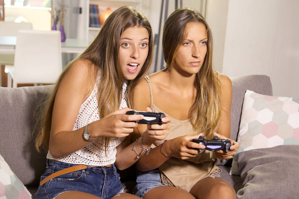 Ragazze sveglie che giocano con i videogiochi a casa divertendosi
 - Foto, immagini