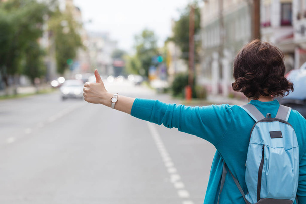 woman with handbag hailing a taxi cab walking in city street - Фото, изображение