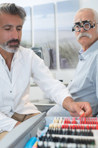 optician in surgery giving man eye test - Foto, immagini