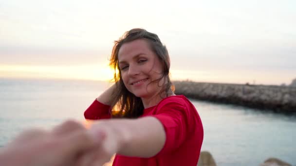 Suivez-moi - heureuse jeune femme en robe rouge tirant les gars main dans la main marchant vers le phare sur la plage au coucher du soleil
 - Séquence, vidéo