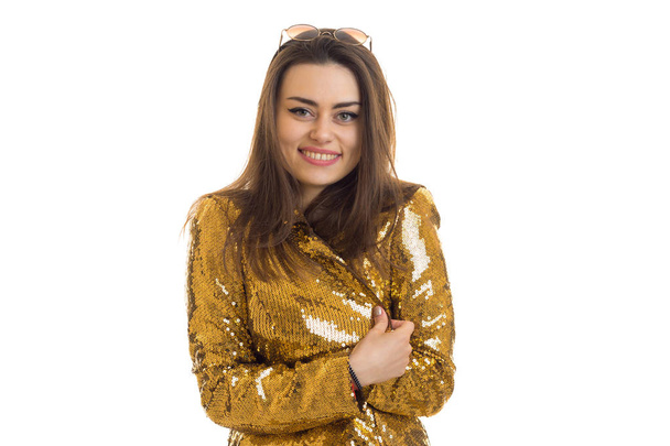 beautiful smiling Lady stands in the gold jacket and suspiciously looking at camera - Foto, imagen