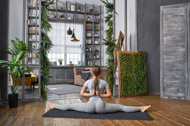 Woman practicing advanced yoga in the living room - Фото, изображение
