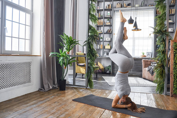 Woman practicing advanced yoga in the living room - Photo, image