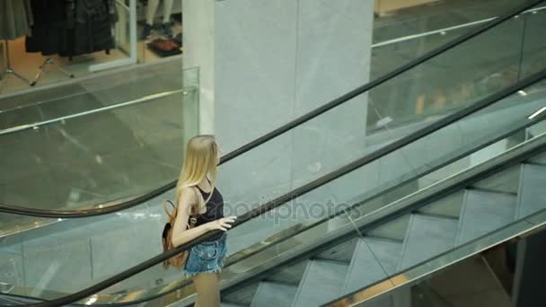 Woman in a mall goes by escalator, transportation stairs, moving staircase - Video