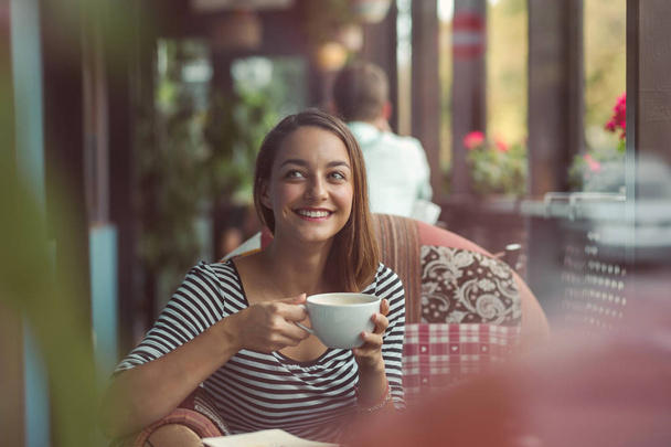 Giovane donna seduta al coperto in un caffè urbano
 - Foto, immagini