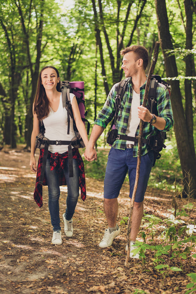 Vacation together. Happy young couple hiking in the woods, holdings hands, smiling, posing for a family portrait for memories, good sunny day - Photo, Image