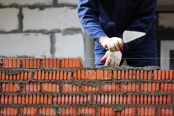 профессиональный строительный работник кладка кирпича и строительство дома на промышленной площадке - Фото, изображение