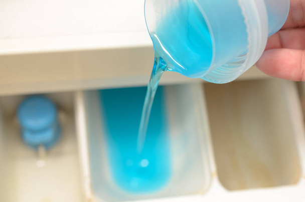 A blue detergent is poured into the washing container. - Foto, Bild