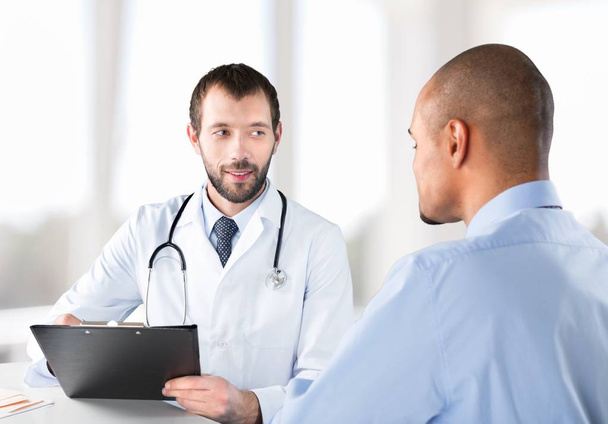 врач улыбается пациенту мужского пола
 - Фото, изображение