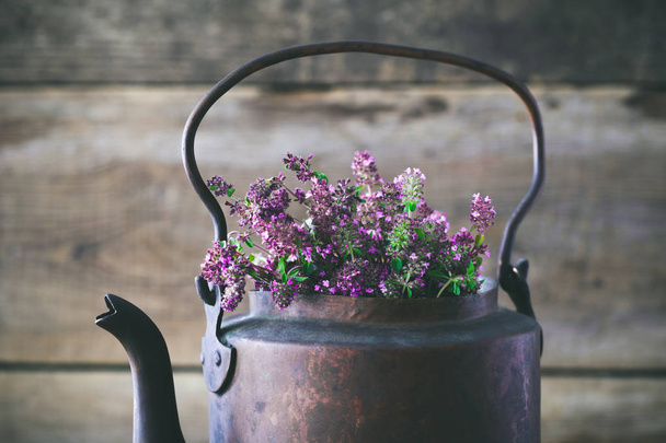 Vintage rustic tea kettle full of thyme flowers for healthy herbal tea. Herbal medicine. - Фото, изображение