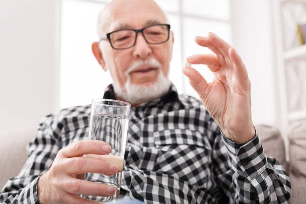 Yaşlı adam elinde bir bardak su ve hapları sahip - Fotoğraf, Görsel