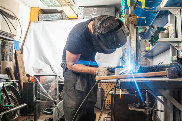 man welds with a welding machine metal - Foto, afbeelding