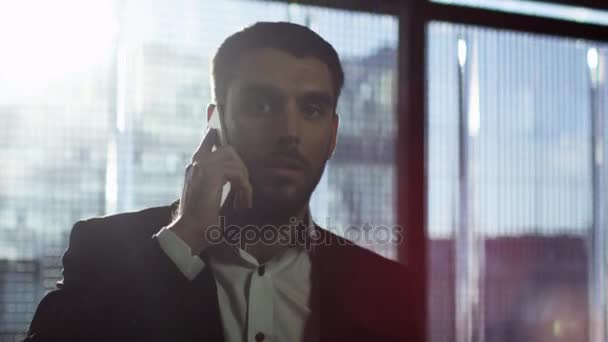 Portrait of a businessman walking and talking on a phone. - Filmati, video