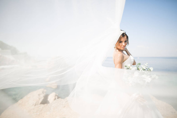 Romantic beautiful bride in white dress posing on the background sea - Fotografie, Obrázek