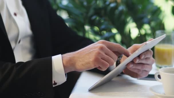 Zakenman in een pak maakt gebruik van een tablet aan de tafel van een restaurant. - Video