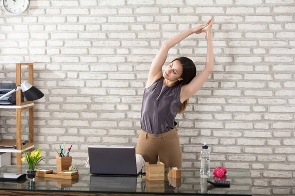 Businesswoman Stretching In Office - Zdjęcie, obraz