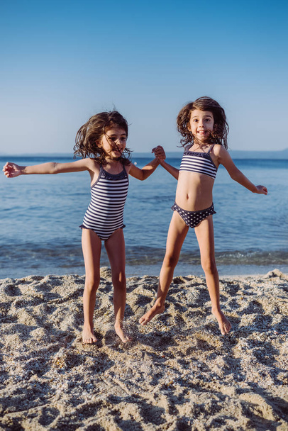 Милые маленькие девочки веселятся на пляже
 - Фото, изображение
