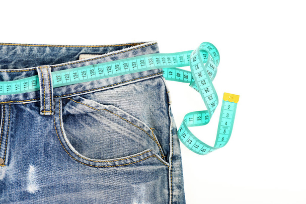 Jeans with measure tape instead of belt on white background - Foto, imagen