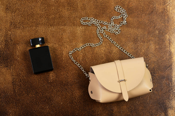 Leather purse and perfume bottle on brown suede background - Фото, изображение