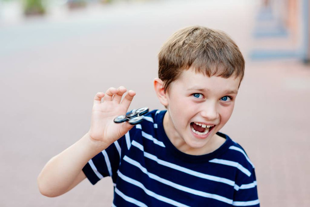Little child boy playing with fidget spinner outdoors - Photo, Image