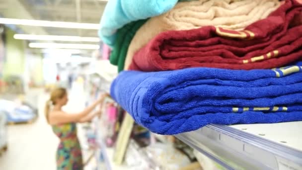 Young girl choosing bath towels textile in apparel clothes shop supermarket, 4k. Slow motion - Footage, Video
