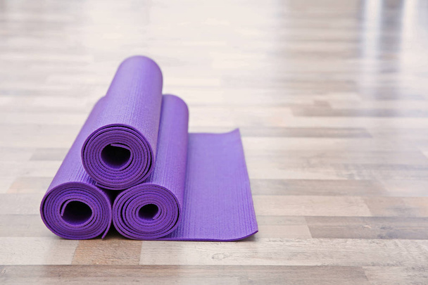 Purple yoga mats on wooden floor - Foto, afbeelding